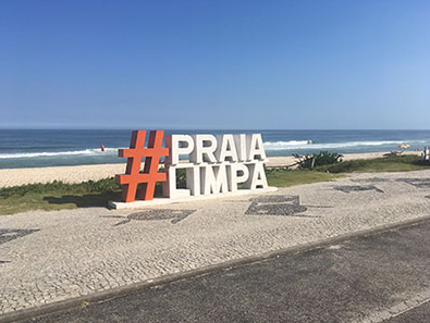 Placa #PRAIA LIMPA na orla da Barra da Tijuca, com o mar ao fundo